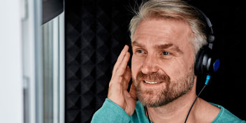 Homem realizando teste auditivo em cabine acústica