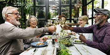 Pessoas brindando e conversando em um almoço em grupo em ambiente acolhedor.