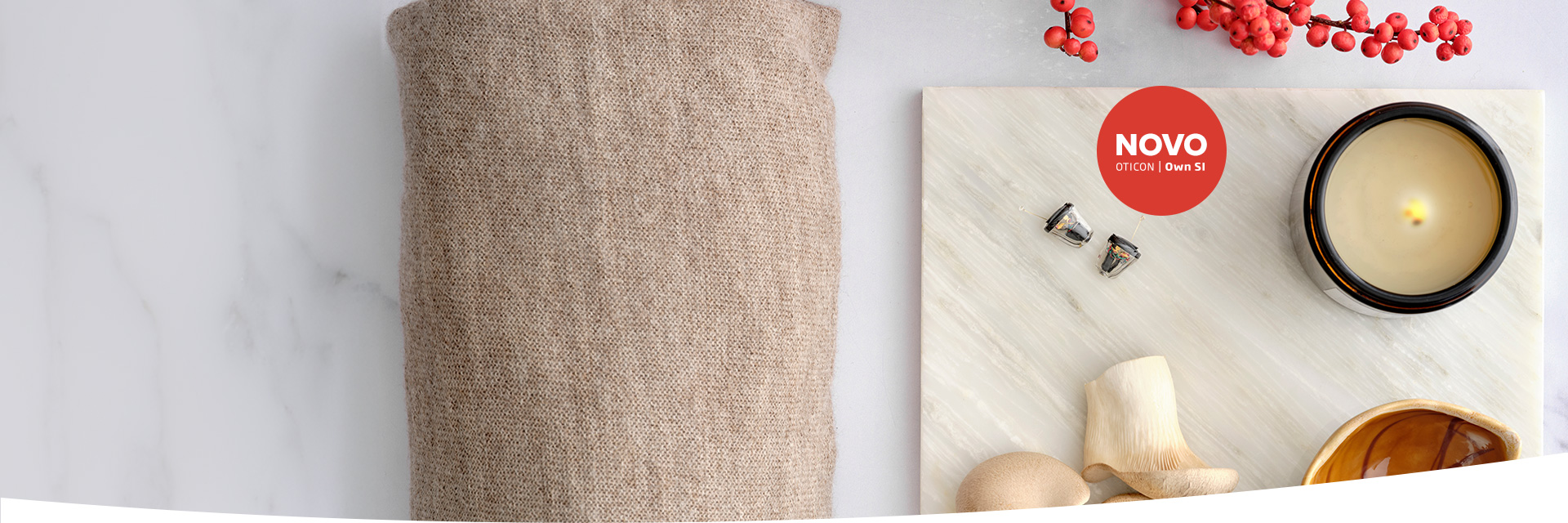 Aparelhos auditivos Oticon Own SI com design discreto ao lado de elementos decorativos elegantes.