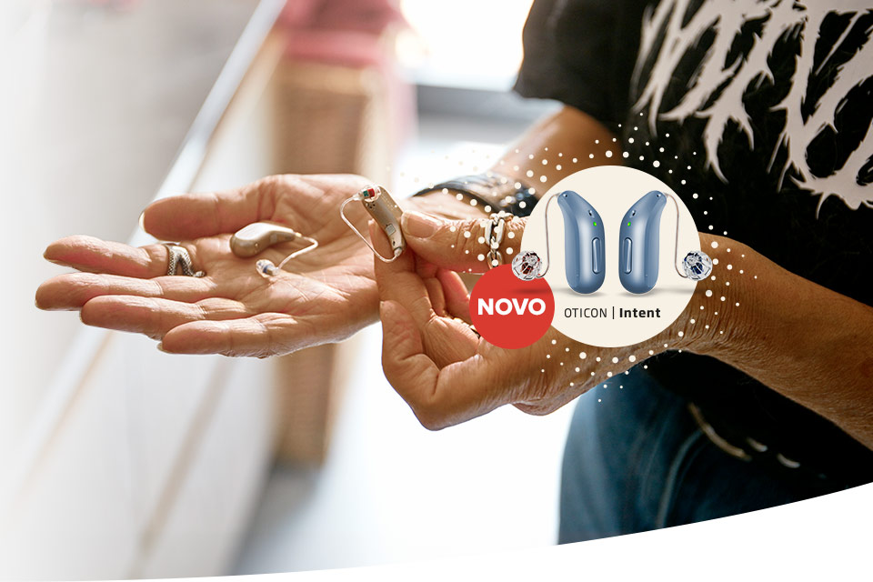 Aparelhos auditivos Oticon Intent em mãos, destaque para o lançamento com design moderno e avançada tecnologia auditiva.