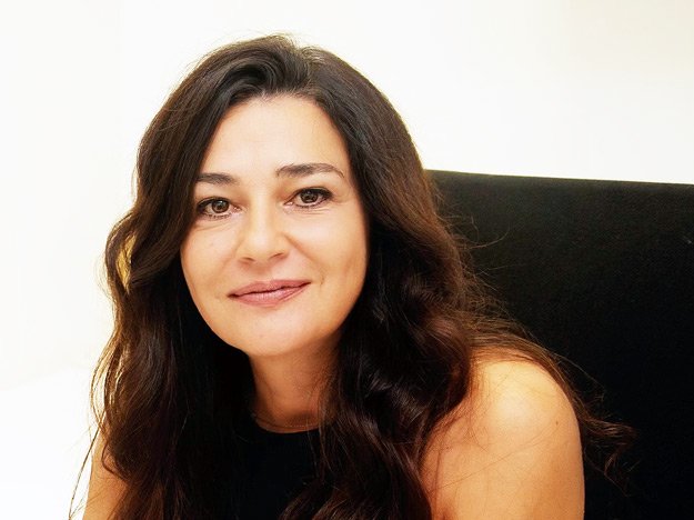 Audiologista com cabelos castanhos ondulados em um consultório.