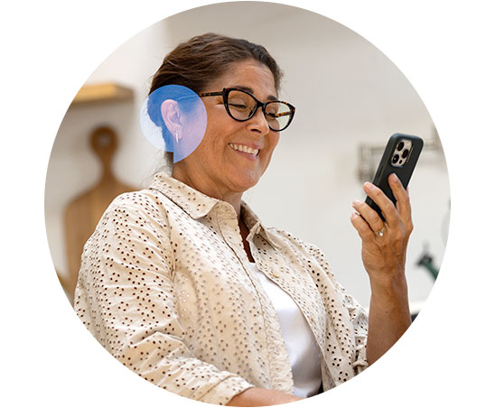 Senhora usando aparelho auditivo e segurando um smartphone