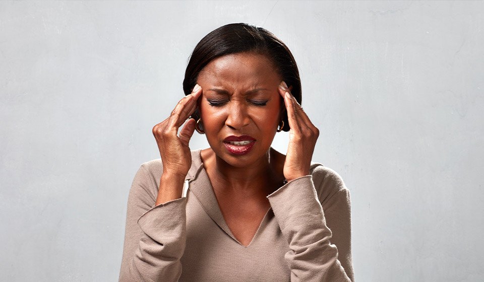 Femme souffrant d’un mal de tête, les mains tenant ses tempes.