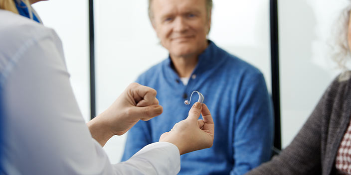 Un audioprothésiste présente un appareil auditif à des clients.