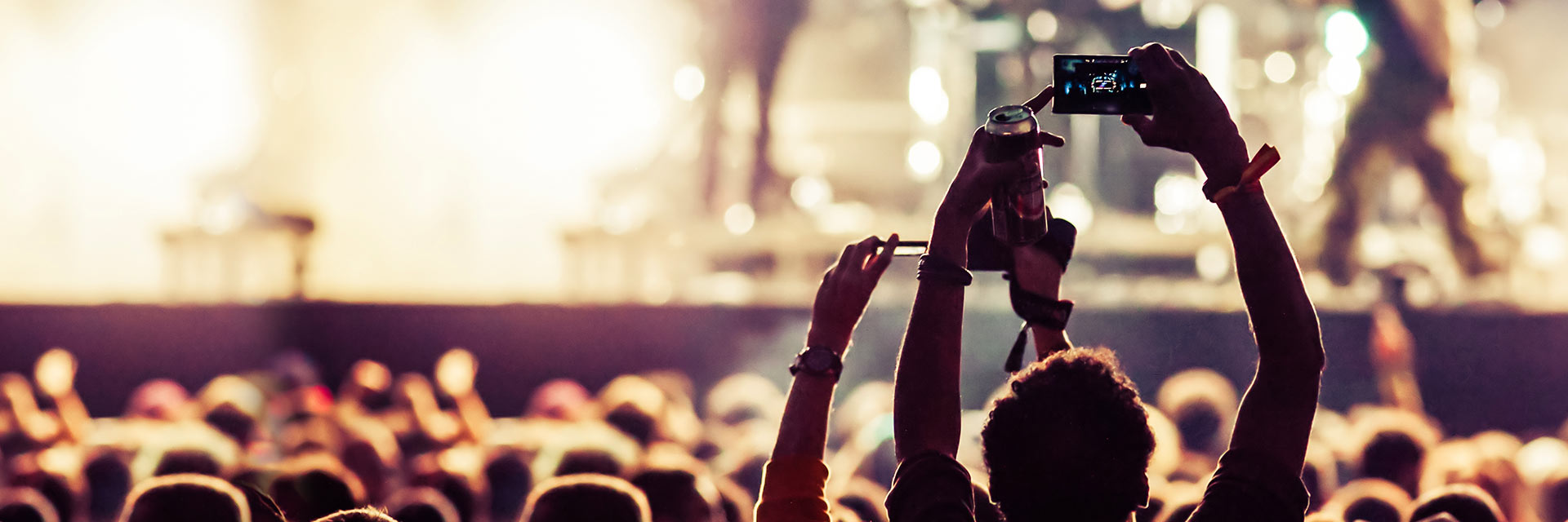 Public assistant à un concert avec une personne filmant la scène avec un smartphone.
