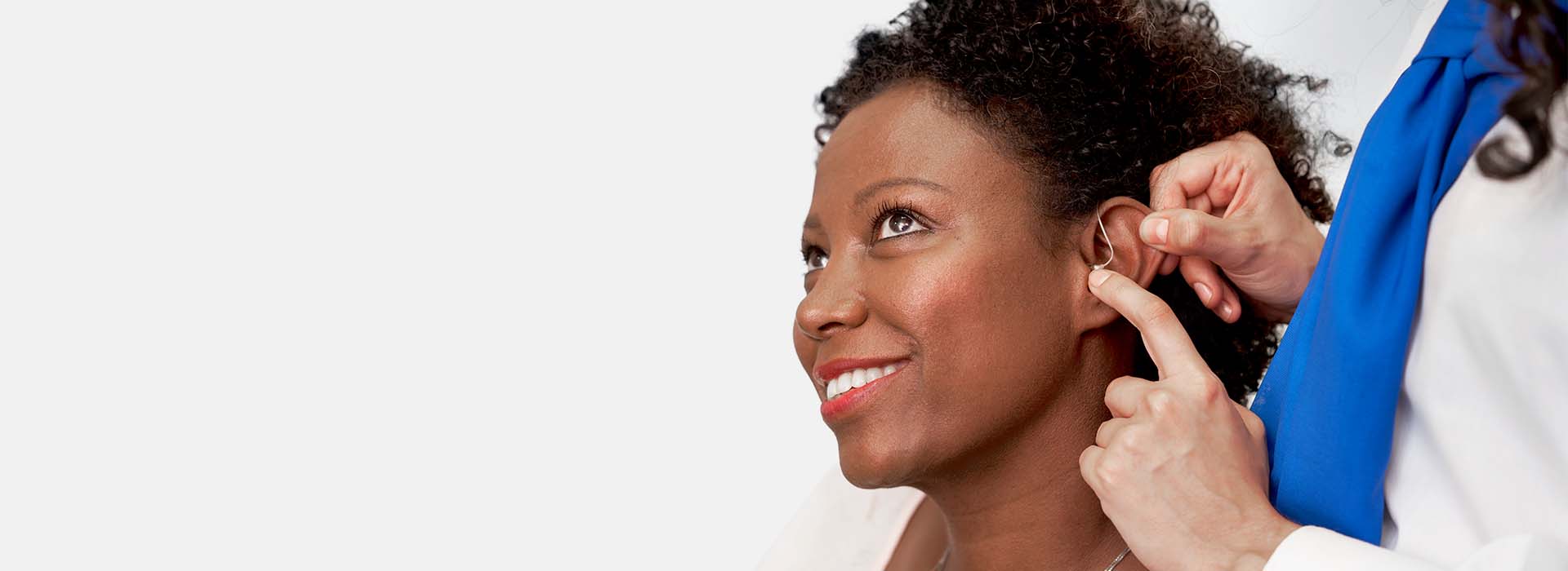 Un audioprothésiste ajuste un appareil auditif dans l’oreille d’une femme.