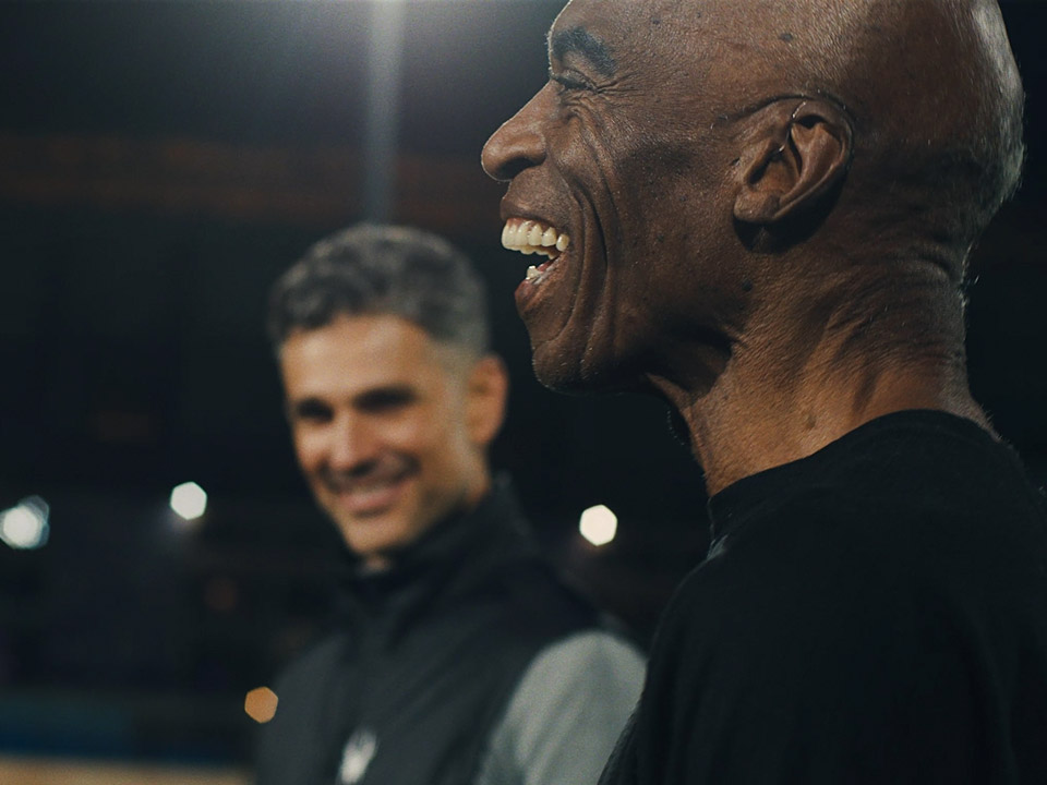 Un homme portant une aide auditive échange avec une autre personne dans un cadre extérieur faiblement éclairé.