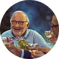 Des personnes partagent un repas en plein air, échangeant et portant des verres de vin.