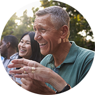 Un homme portant un appareil auditif en discussion en plein air avec des personnes en arrière-plan.