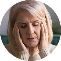 Une femme d'âge moyen souffre d'inconfort ou de douleur, tenant sa tête avec ses mains.