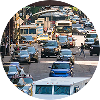 Circulation dense en centre-ville avec voitures, bus et piétons.