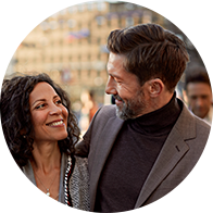 Un homme et une femme partagent un moment complice en souriant, dans un cadre urbain.