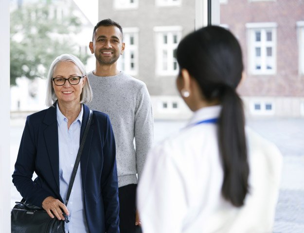 Un audioprothésiste accueille un couple dans une clinique spécialisée en soins auditifs.