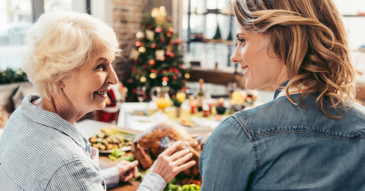 Ältere Frau und jüngere Frau führen ein ruhiges Gespräch bei festlichem Essen – freundliche Gesprächssituation mit Blickkontakt in entspannter Umgebung.