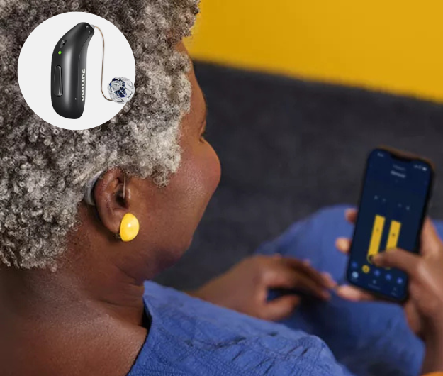 EIne Dame nutzt die Philips HearLink 2 App auf IHrem Smartphone. Ein Philips HearLink Hörgerät wird darüber eingeblendet.