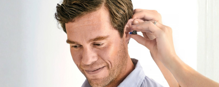 Ein junger Mann bekommt das Oticon Zeal Hörgerät in sein Ohr eingesetzt