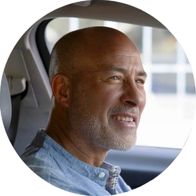 Ein Mann im Fahrersitz eines Autos, der ein Oticon Zeal trägt.