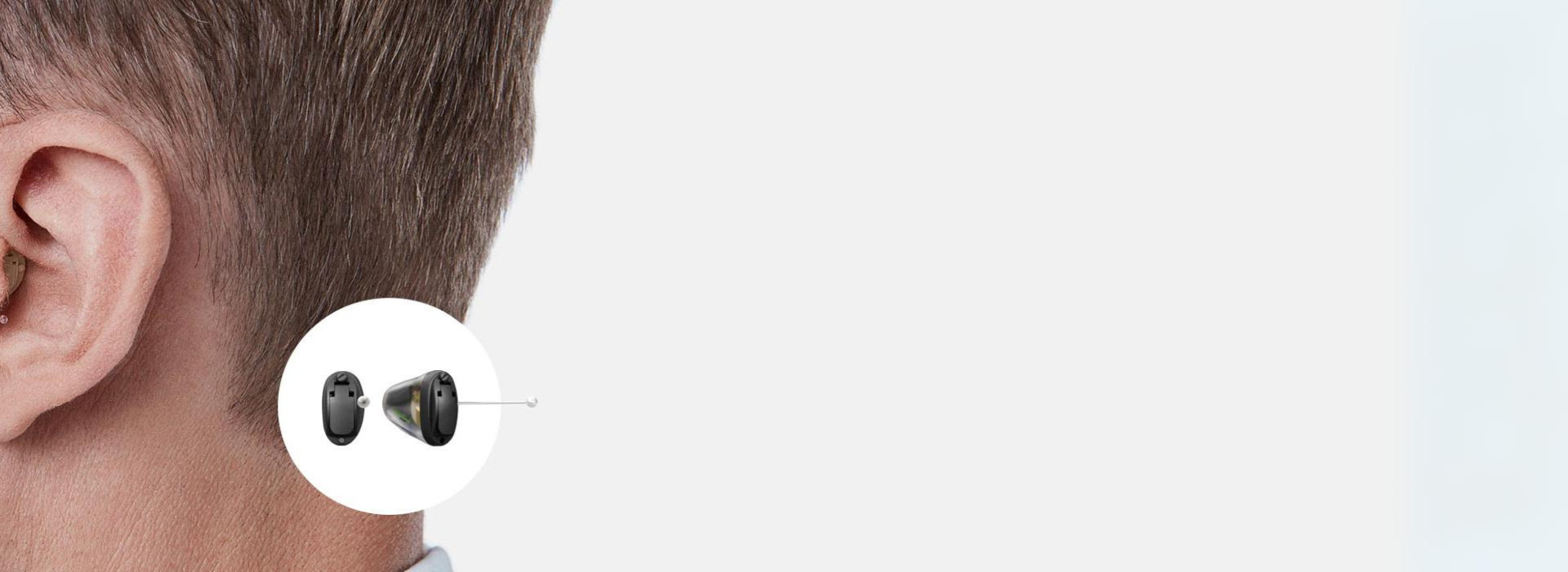 Zwei kleine nahezu unsichtbare Hörgeräte auf einer Handfläche