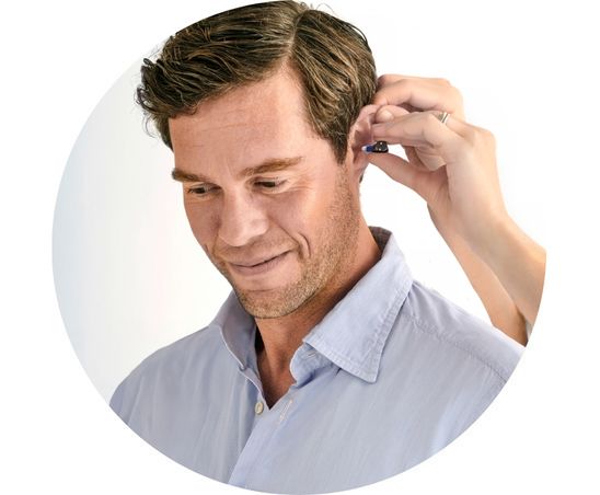 Ein junger Mann bekommt das Oticon Zeal Hörgerät in sein Ohr eingesetzt