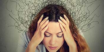 Kvinde med hænderne på hovedet, der illustrerer stress eller tinnitus.