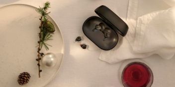 Oticon Zeal-høreapparater på et bord med hvid dug, gran og julekugler.