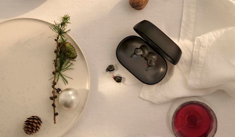 Oticon Zeal-høreapparater på et bord med hvid dug, gran og julekugler.