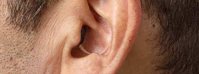 Nærbillede af Oticon Zeal-høreapparat i øret på en mand. 