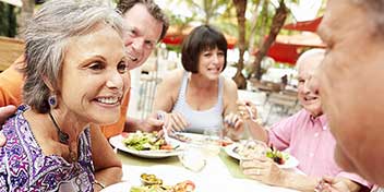 Flere mennesker nyder et måltid sammen ved et udendørs bord.