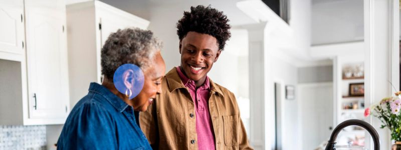 Ældre kvinde og teenagedreng er i køkkenet sammen. Drengen smiler til kvinden, som måske er hans bedstemor.