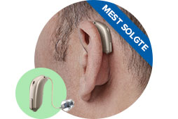 Et diskret høreapparat sidder bag øret på en person, forbundet med en tynd ledning. Teksten ’MEST SOLGTE’ ses på en blå bannerdetalje øverst til højre.