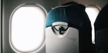 Respaldo de un asiento de avión junto a la ventanilla iluminada