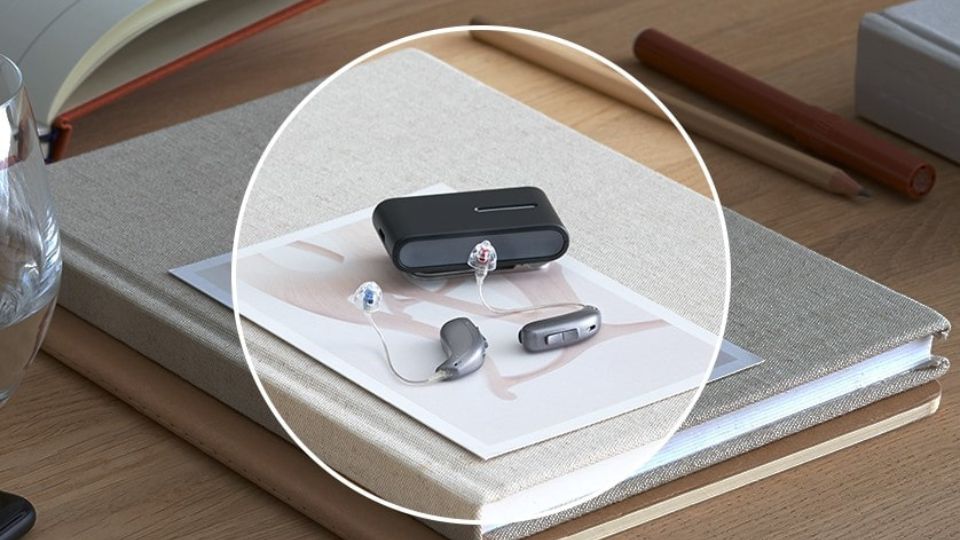 audífonos para pérdida auditiva sobre una superficie con libros y accesorios