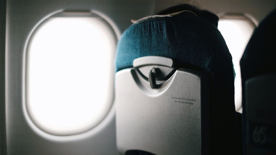 Respaldo de un asiento de avión junto a la ventanilla iluminada