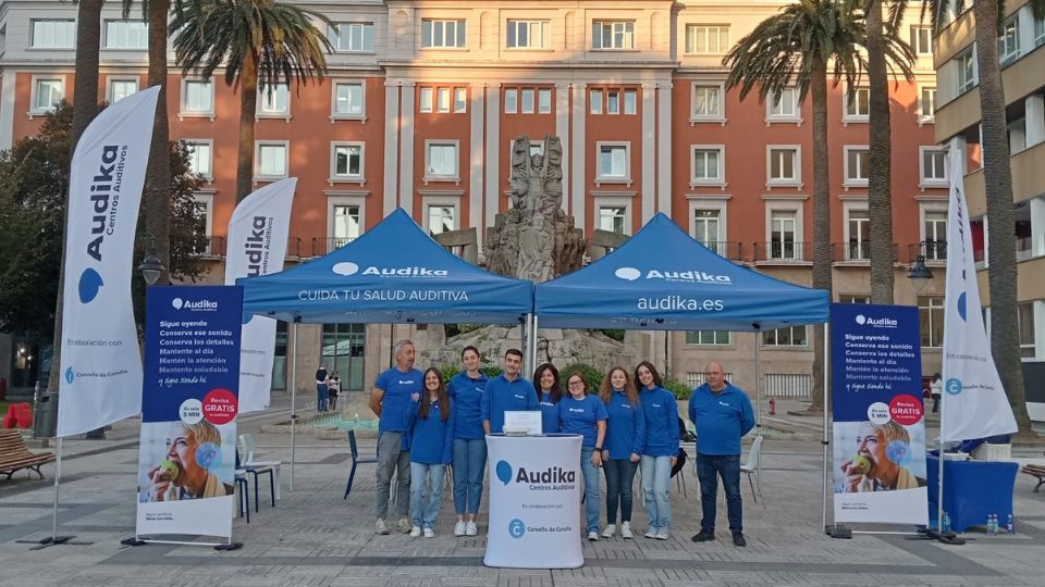 Equipo Audika en la campaña de concienciación sobre salud auditiva en una plaza pública con carpas informativas y materiales promocionales.