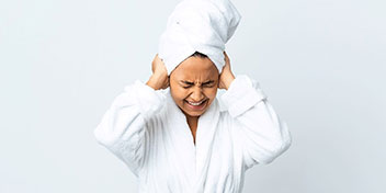 mujer joven con dolor de oídos y toalla en la cabeza