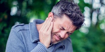 hombre tocándose el oído debido a tinnitus o acúfenos