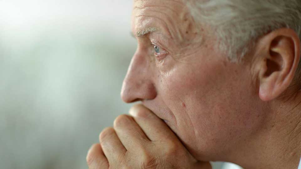 Una oreja de una persona mayor, sin audífono visible, en un entorno iluminado y desenfocado, posiblemente relacionado con servicios de audición o evaluación auditiva en una clínica.