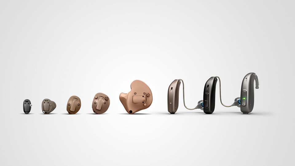 Audífonos de distintos tamaños y colores, desde modelos intrauriculares hasta retroauriculares, alineados sobre un fondo blanco. Representan opciones avanzadas para el cuidado auditivo en clínicas especializadas.
