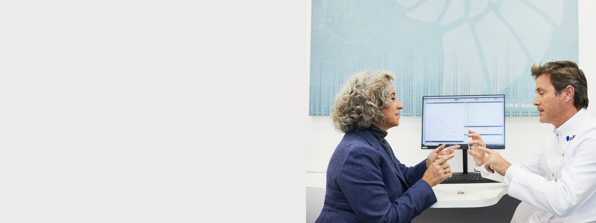 La imagen muestra un audioprotesista hablando con una persona con pérdida auditiva frente a una pantalla mostrando un audiograma