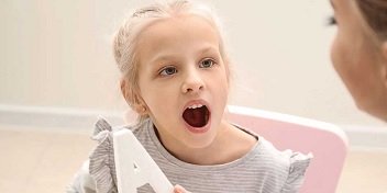 niña practicando ejercicios de terapia del habla con un especialista en audición