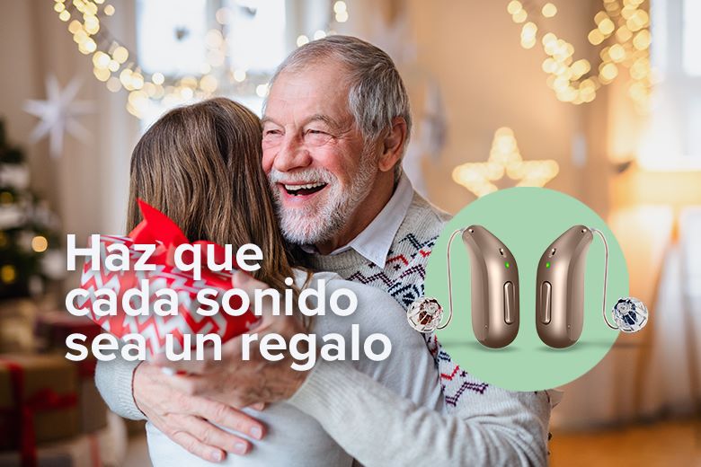 abuelo abrazando su nieta con regalo en la mano. audifonos audika en destaque