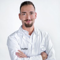 Javier Ríos, audioprotesista certificado en Audika Segovia con bata blanca y brazos cruzados.