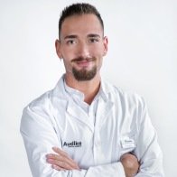 Javier Ríos, audioprotesista certificado en Audika Segovia con bata blanca y brazos cruzados.