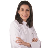 Audioprotesista en Audika Reus, Lucía Carmona, con bata blanca y brazos cruzados