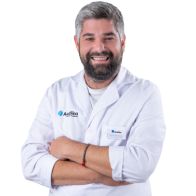 Especialista en audición Dario López con bata blanca y logotipo de Audífonos en el pecho.