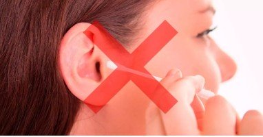 Una oreja humana vista de perfil con cabello castaño alrededor, resaltada mediante un filtro rojo en un entorno desenfocado. No se observa un audífono ni texto identificable.