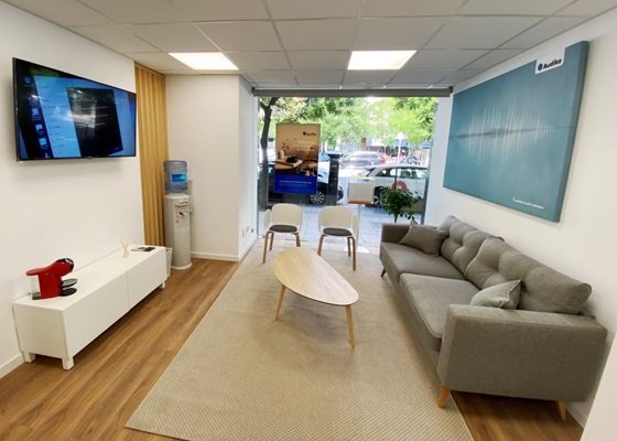 Sala de espera moderna en un centro Audika, con sofá gris, mesa de madera y decoración minimalista.