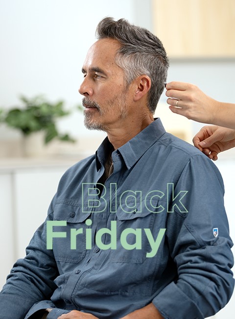 Un hombre está sentado mientras le adaptan unos audífonos, mostrando el texto Black Friday en la imagen