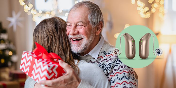 abuelo abrazando a su nieta con regalo en la mano. Se ven destacados los audifonos  audika