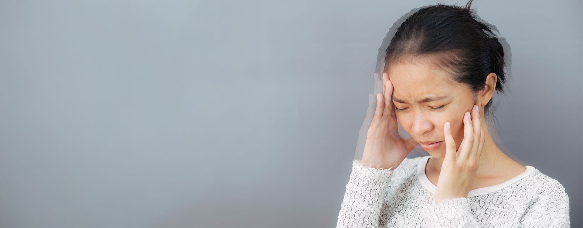 Persona con sensación de vértigo y pérdida de equilibrio, apoyándose en la pared, síntoma frecuente de la neuritis vestibular.